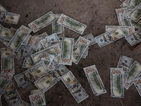 Counterfeit U.S. 100 dollar banknotes on the floor inside a compound in O'Smach used for scam operations, at the Chong Chom-O'Smach border crossing, which was bombed and occupied by the Thai military in December following clashes between Thailand and