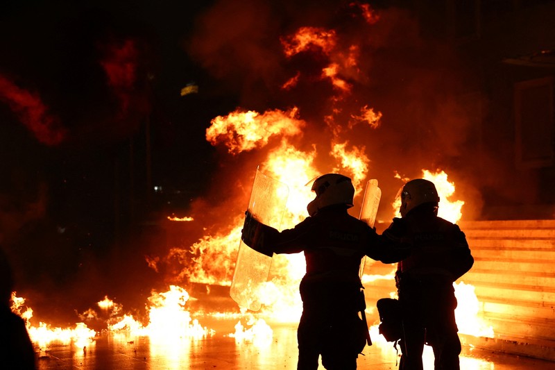 Para petugas polisi bereaksi terhadap bom molotov selama protes anti-pemerintah, yang dipicu oleh penyelidikan korupsi terhadap Wakil Perdana Menteri Belinda Balluku, di depan Gedung Parlemen di Tirana, Albania, 10 Februari 2026. (REUTERS/Florion Goga)
