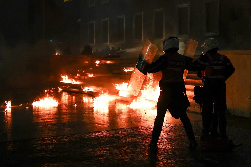 Para petugas polisi bereaksi terhadap bom molotov selama protes anti-pemerintah, yang dipicu oleh penyelidikan korupsi terhadap Wakil Perdana Menteri Belinda Balluku, di depan Gedung Parlemen di Tirana, Albania, 10 Februari 2026. (REUTERS/Florion Goga)