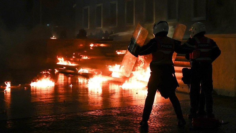 Para petugas polisi bereaksi terhadap bom molotov selama protes anti-pemerintah, yang dipicu oleh penyelidikan korupsi terhadap Wakil Perdana Menteri Belinda Balluku, di depan Gedung Parlemen di Tirana, Albania, 10 Februari 2026. (REUTERS/Florion Goga)