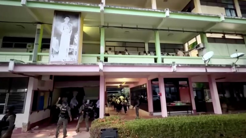 Sejumlah polisi bersenjata mengevakuasi pelajar saat pria bersenjata menyandera sejumlah siswa dan guru di Songkhla, Thailand selatan, 11 Februari 2026. (Reuters)