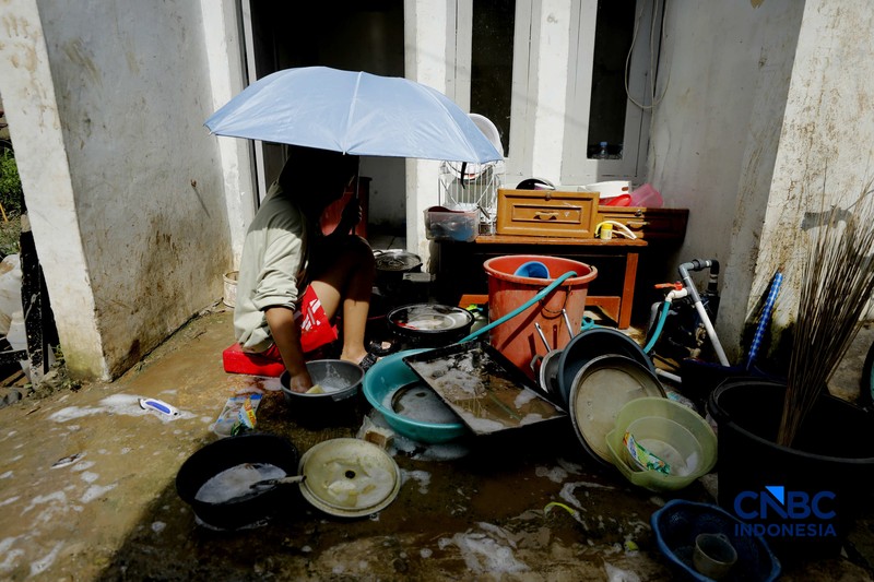 Warga membersihkan properti rumah yang terkena banjir di Kampung Carewed, Desa Cijayanti, Babakan Madang, Kabupaten Bogor, Jawa Barat, Kamis (12/2/2026). (CNBC Indonesia/Tri Susilo)