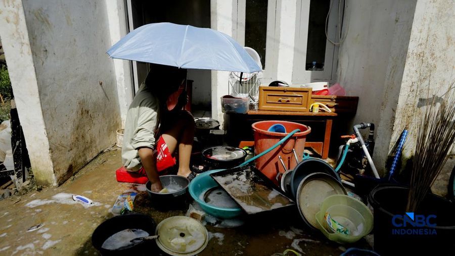Warga membersihkan properti rumah yang terkena banjir di Kampung Carewed, Desa Cijayanti, Babakan Madang, Kabupaten Bogor, Jawa Barat, Kamis (12/2/2026). (CNBC Indonesia/Tri Susilo)