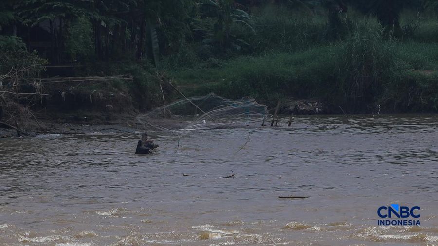 Warga mencari ikan pada aliran Sungai Cisadane yang tercemar limbah di Kota Tangerang, Banten, Kamis (12/2/2026). (CNBC Indonesia/Faisal Rahman)