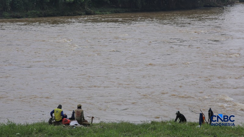 Warga mencari ikan pada aliran Sungai Cisadane yang tercemar limbah di Kota Tangerang, Banten, Kamis (12/2/2026). (CNBC Indonesia/Faisal Rahman)