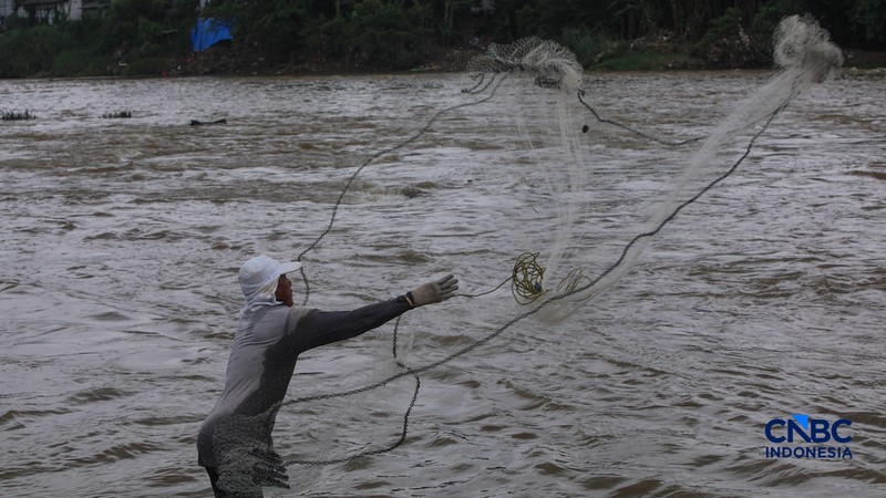 Warga mencari ikan pada aliran Sungai Cisadane yang tercemar limbah di Kota Tangerang, Banten, Kamis (12/2/2026). (CNBC Indonesia/Faisal Rahman)