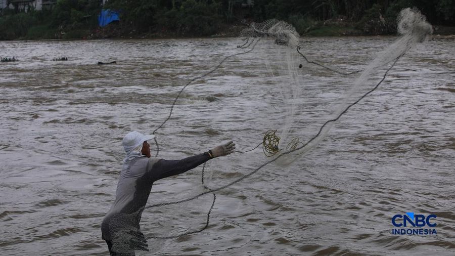Warga mencari ikan pada aliran Sungai Cisadane yang tercemar limbah di Kota Tangerang, Banten, Kamis (12/2/2026). (CNBC Indonesia/Faisal Rahman)
