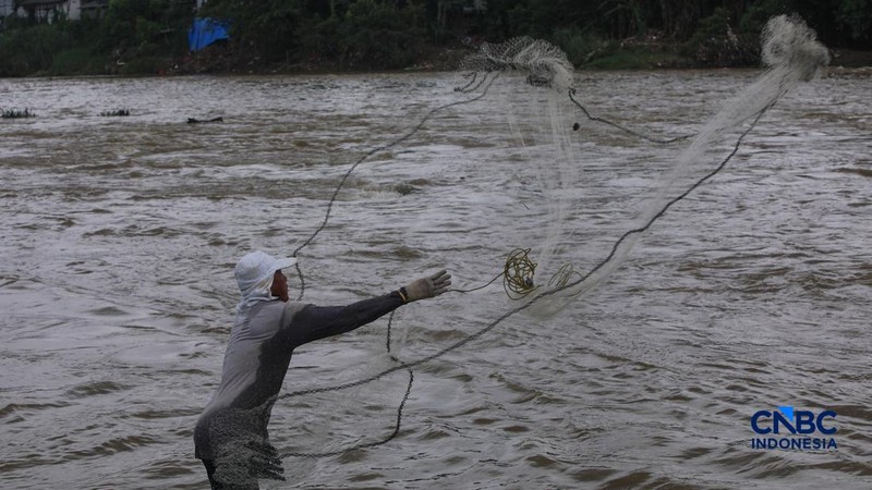 Warga mencari ikan pada aliran Sungai Cisadane yang tercemar limbah di Kota Tangerang, Banten, Kamis (12/2/2026). (CNBC Indonesia/Faisal Rahman)