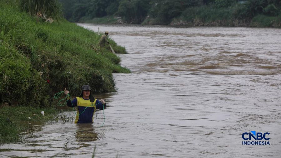 Warga mencari ikan pada aliran Sungai Cisadane yang tercemar limbah di Kota Tangerang, Banten, Kamis (12/2/2026). (CNBC Indonesia/Faisal Rahman)