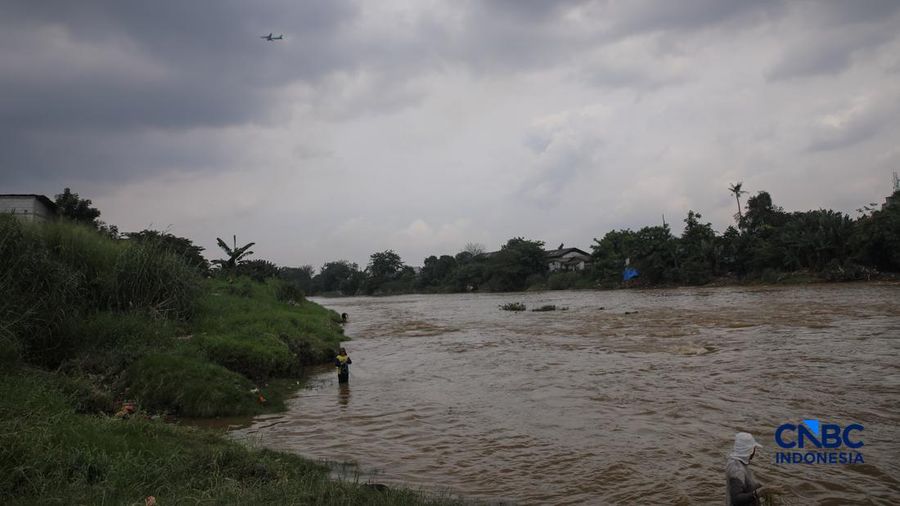 Warga mencari ikan pada aliran Sungai Cisadane yang tercemar limbah di Kota Tangerang, Banten, Kamis (12/2/2026). (CNBC Indonesia/Faisal Rahman)