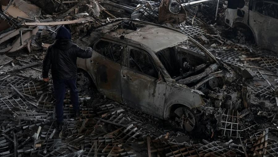 Warga berjalan di dekat mobil-mobil yang rusak di lokasi serangan pesawat tak berawak Rusia, di tengah serangan Rusia terhadap Ukraina, di Odesa, Ukraina, 13 Februari 2026. (REUTERS/Nina Liashonok)
