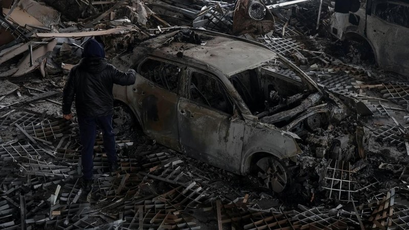 Warga berjalan di dekat mobil-mobil yang rusak di lokasi serangan pesawat tak berawak Rusia, di tengah serangan Rusia terhadap Ukraina, di Odesa, Ukraina, 13 Februari 2026. (REUTERS/Nina Liashonok)