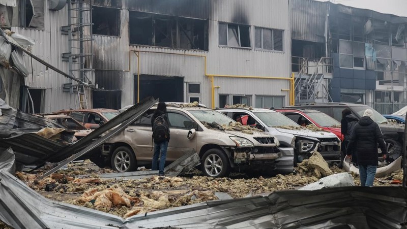 Warga berjalan di dekat mobil-mobil yang rusak di lokasi serangan pesawat tak berawak Rusia, di tengah serangan Rusia terhadap Ukraina, di Odesa, Ukraina, 13 Februari 2026. (REUTERS/Nina Liashonok)