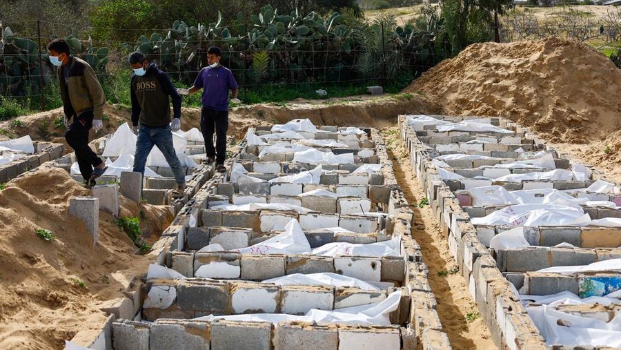 A man gestures next to bodies placed in graves during a mass burial of unidentified Palestinians, whose bodies were released after being held in Israel during the war, in Deir Al-Balah, in the central Gaza Strip, February 13, 2026. REUTERS/Mahmoud Issa