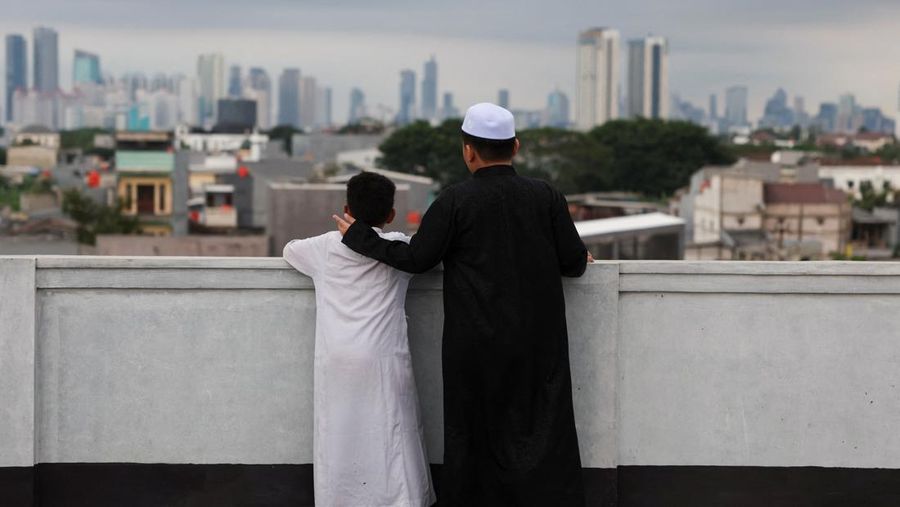 Para pria Muslim berkumpul untuk mengamati posisi bulan, guna menentukan awal bulan suci puasa Ramadan, di atap masjid Al-Musyari'in di Jakarta, Indonesia, 17 Februari 2026. (REUTERS/Ajeng Dinar Ulfiana)