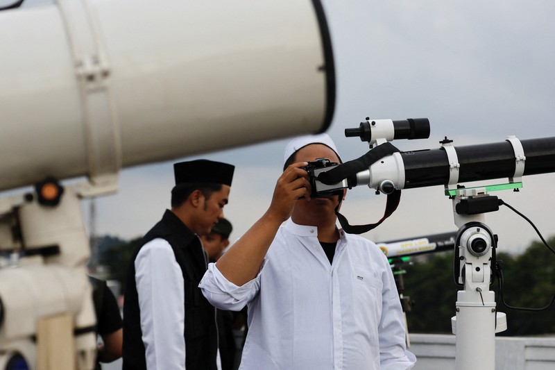 Para pria Muslim berkumpul untuk mengamati posisi bulan, guna menentukan awal bulan suci puasa Ramadan, di atap masjid Al-Musyari'in di Jakarta, Indonesia, 17 Februari 2026. (REUTERS/Ajeng Dinar Ulfiana)