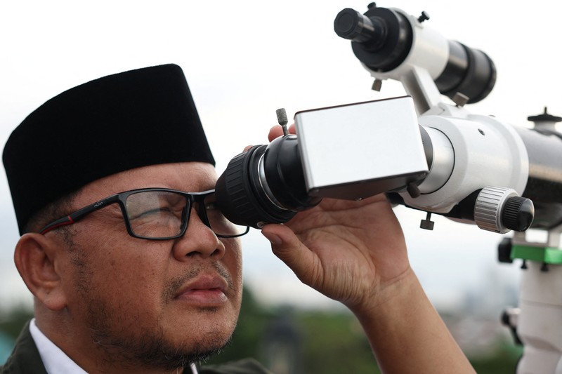 Para pria Muslim berkumpul untuk mengamati posisi bulan, guna menentukan awal bulan suci puasa Ramadan, di atap masjid Al-Musyari'in di Jakarta, Indonesia, 17 Februari 2026. (REUTERS/Ajeng Dinar Ulfiana)