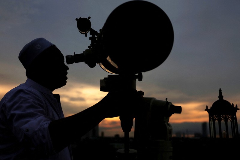 Para pria Muslim berkumpul untuk mengamati posisi bulan, guna menentukan awal bulan suci puasa Ramadan, di atap masjid Al-Musyari'in di Jakarta, Indonesia, 17 Februari 2026. (REUTERS/Ajeng Dinar Ulfiana)
