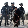 Seorang wanita Palestina, yang dilarang masuk ke Yerusalem, berjalan di samping anggota pasukan Israel, saat orang-orang menuju kompleks Al-Aqsa, yang juga dikenal oleh orang Yahudi sebagai Bukit Bait Suci, di Kota Tua Yerusalem, untuk menghadiri sal