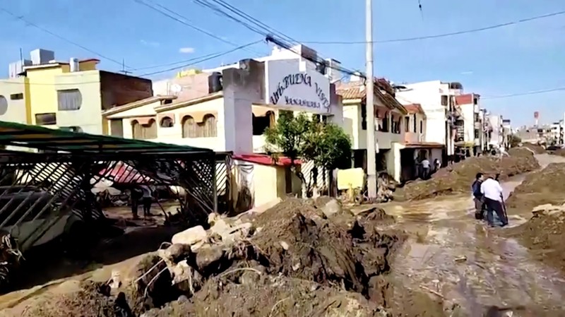 Warga membersihkan jalan setelah hujan lebat menyebabkan lingkungan tersebut tergenang lumpur dan puing-puing, di Arequipa, Peru, 19 Februari 2026. (REUTERS/Oswald Charca)