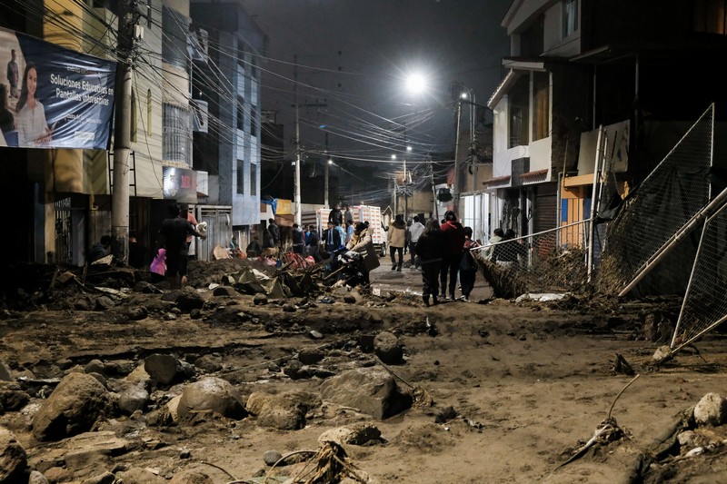 Warga membersihkan jalan setelah hujan lebat menyebabkan lingkungan tersebut tergenang lumpur dan puing-puing, di Arequipa, Peru, 19 Februari 2026. (REUTERS/Oswald Charca)