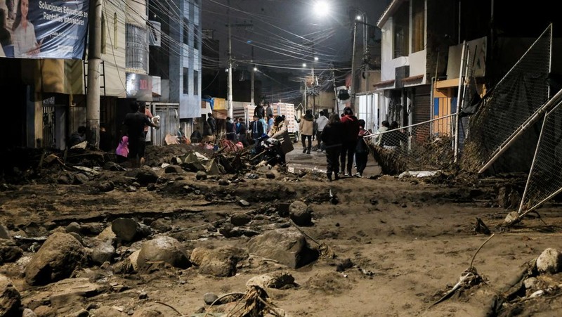 Warga membersihkan jalan setelah hujan lebat menyebabkan lingkungan tersebut tergenang lumpur dan puing-puing, di Arequipa, Peru, 19 Februari 2026. (REUTERS/Oswald Charca)