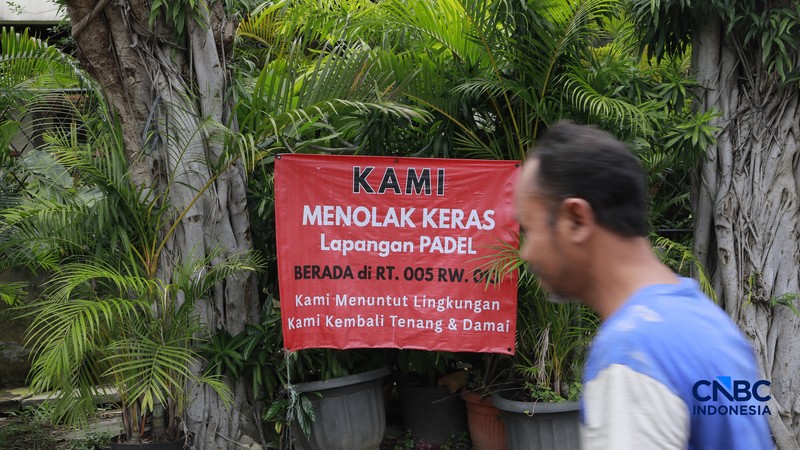 Deretan spanduk penolakan terbentang di pagar dan sudut jalan lingkungan RT 05/13, Pulomas, Jakarta Timur,  Selasa, (24/2/2026). (CNBC Indonesia/Muhammad Sabki)