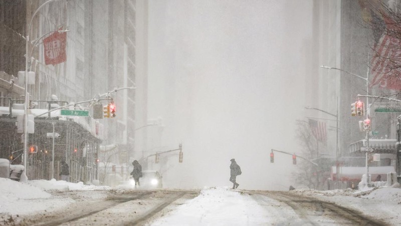 Seorang pejalan kaki berjalan di jalan saat salju turun selama badai musim dingin di Kota New York, AS, 23 Februari 2026. (REUTERS/Jeenah Moon)