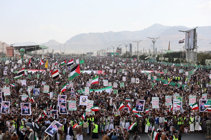 Ribuan orang membawa poster bergambar mendiang Pemimpin Tertinggi Iran, Ayatollah Ali Khamenei, saat menggelar aksi unjuk rasa menentang serangan Israel dan Amerika Serikat terhadap Iran di Sanaa, Yaman, Minggu (1/3/2026). Aksi tersebut berlangsung di tengah meningkatnya ketegangan kawasan menyusul kabar pembunuhan pemimpin tertinggi Iran itu. (REUTERS/Khaled Abdullah)