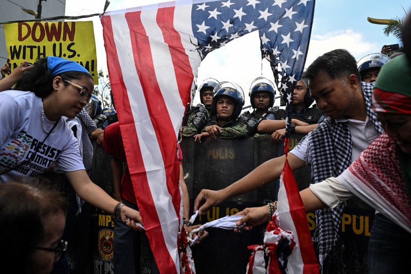 Para pengunjuk rasa membakar bendera AS selama demonstrasi menentang serangan AS-Israel terhadap Iran, di tengah konflik dengan Iran, di dekat Kedutaan Besar AS di Manila, Filipina, 3 Maret 2026. (REUTERS/Noel Celis)