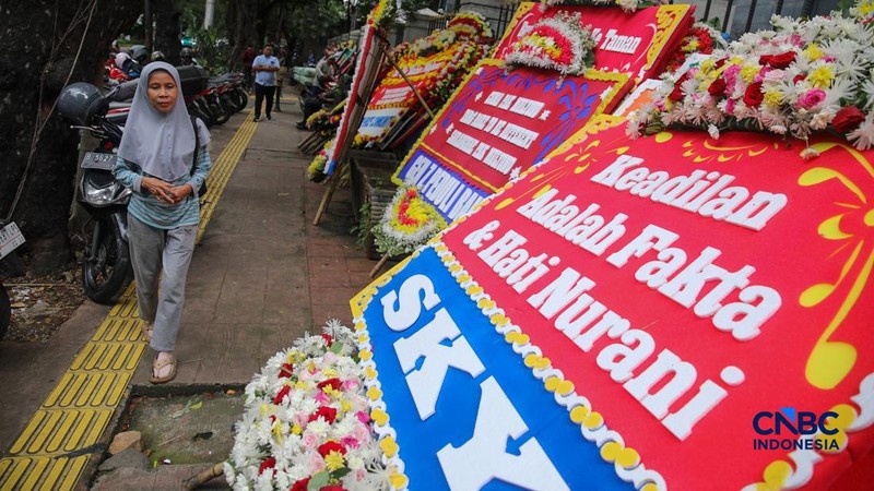 Warga berjalan di dekat deretan karangan bunga dukungan untuk Hakim anggota Mulyono di depan Pengadilan Tipikor, Jakarta, Rabu (4/3/2026). (CNBC Indonesia/Faisal Rahman)