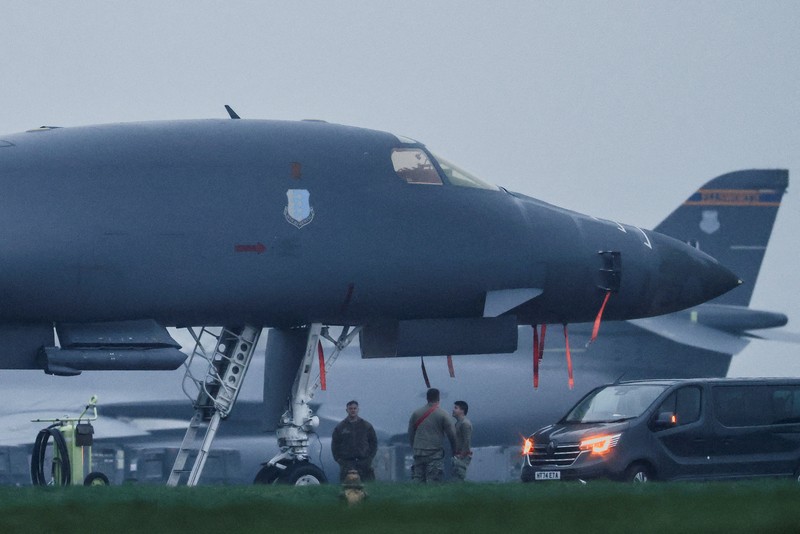 Sebuah pesawat Boeing C-17A Globemaster milik Angkatan Udara Amerika Serikat (USAF) mendarat di belakang pesawat pembom B-1B USAF yang diparkir di samping landasan pacu di pangkalan udara RAF Fairford, yang digunakan oleh USAF, di tengah konflik AS-Israel dengan Iran, di Fairford, Inggris, 8 Maret 2026. (REUTERS/Toby Melville)