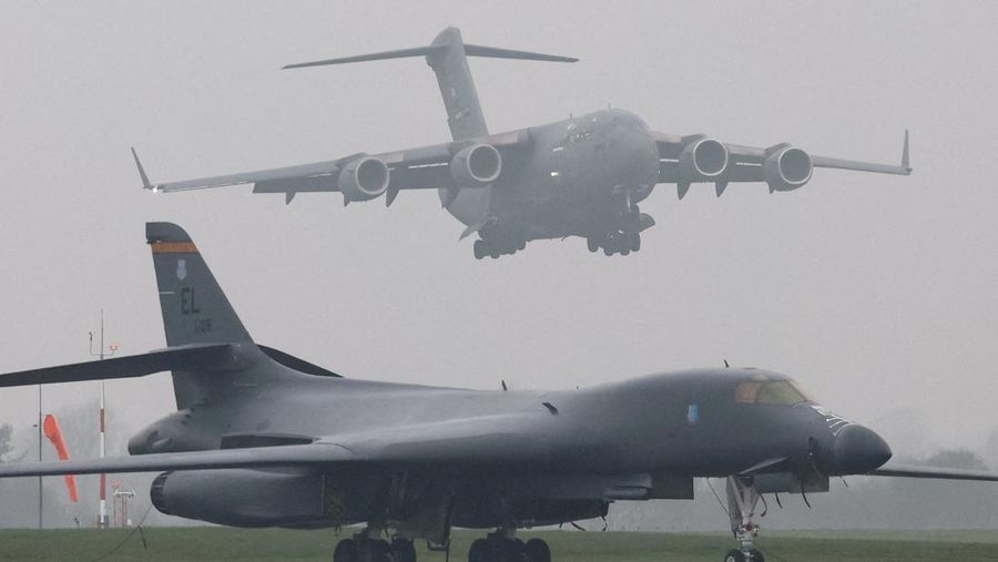Sebuah pesawat Boeing C-17A Globemaster milik Angkatan Udara Amerika Serikat (USAF) mendarat di belakang pesawat pembom B-1B USAF yang diparkir di samping landasan pacu di pangkalan udara RAF Fairford, yang digunakan oleh USAF, di tengah konflik AS-Israel dengan Iran, di Fairford, Inggris, 8 Maret 2026. (REUTERS/Toby Melville)