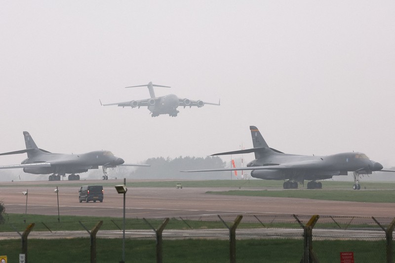Sebuah pesawat Boeing C-17A Globemaster milik Angkatan Udara Amerika Serikat (USAF) mendarat di belakang pesawat pembom B-1B USAF yang diparkir di samping landasan pacu di pangkalan udara RAF Fairford, yang digunakan oleh USAF, di tengah konflik AS-Israel dengan Iran, di Fairford, Inggris, 8 Maret 2026. (REUTERS/Toby Melville)