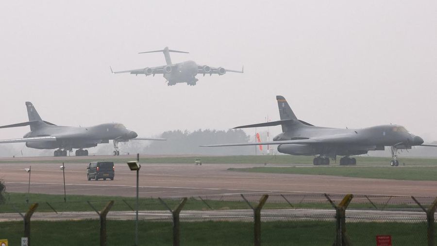 Sebuah pesawat Boeing C-17A Globemaster milik Angkatan Udara Amerika Serikat (USAF) mendarat di belakang pesawat pembom B-1B USAF yang diparkir di samping landasan pacu di pangkalan udara RAF Fairford, yang digunakan oleh USAF, di tengah konflik AS-Israel dengan Iran, di Fairford, Inggris, 8 Maret 2026. (REUTERS/Toby Melville)