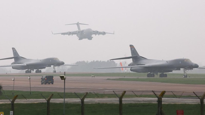 Sebuah pesawat Boeing C-17A Globemaster milik Angkatan Udara Amerika Serikat (USAF) mendarat di belakang pesawat pembom B-1B USAF yang diparkir di samping landasan pacu di pangkalan udara RAF Fairford, yang digunakan oleh USAF, di tengah konflik AS-Israel dengan Iran, di Fairford, Inggris, 8 Maret 2026. (REUTERS/Toby Melville)