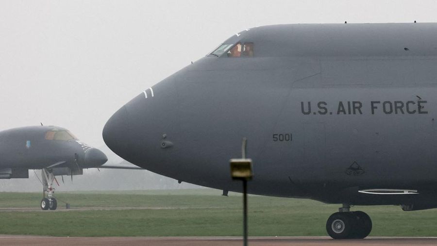 Sebuah pesawat Boeing C-17A Globemaster milik Angkatan Udara Amerika Serikat (USAF) mendarat di belakang pesawat pembom B-1B USAF yang diparkir di samping landasan pacu di pangkalan udara RAF Fairford, yang digunakan oleh USAF, di tengah konflik AS-Israel dengan Iran, di Fairford, Inggris, 8 Maret 2026. (REUTERS/Toby Melville)
