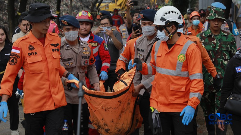 Sejumlah petugas mengevakuasi jenazah dengan kantung saat melakukan pencarian korban longsor gunungan sampah di Tempat Pengolahan Sampah Terpadu (TPST) Bantargebang, Bekasi, Jawa Barat, Senin (9/3/2026). (CNBC Indonesia/Muhammad Sabki)