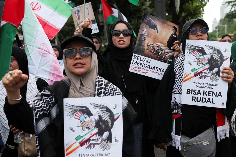 Para wanita membawa plakat selama protes di tengah konflik AS-Israel dengan Iran, di luar kedutaan besar AS di Jakarta, Indonesia, 9 Maret 2026. (REUTERS/Ajeng Dinar Ulfiana)