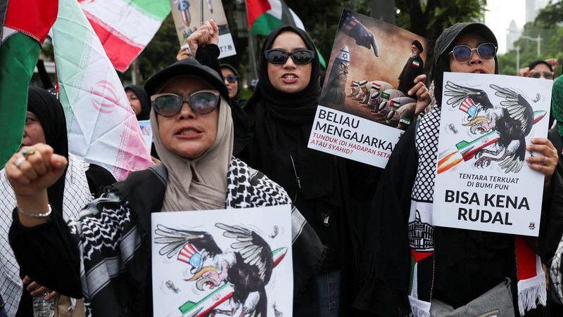 Para wanita membawa plakat selama protes di tengah konflik AS-Israel dengan Iran, di luar kedutaan besar AS di Jakarta, Indonesia, 9 Maret 2026. (REUTERS/Ajeng Dinar Ulfiana)