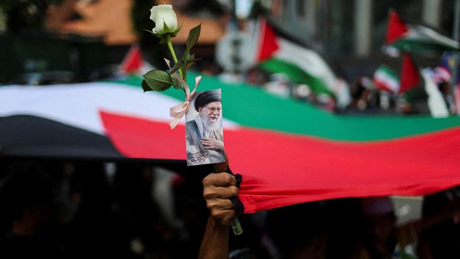 Para pendukung pro-Palestina mengibarkan bendera Palestina dan membawa replika Masjid Al-Aqsa selama unjuk rasa ke Kedutaan Besar AS untuk memperingati Hari al-Quds (Yerusalem), yang diprakarsai oleh Ruhollah Khomeini, pemimpin Revolusi Islam Iran tahun 1979 dan diperingati pada Jumat terakhir bulan puasa Ramadhan untuk menunjukkan solidaritas dengan Palestina dan penentangan terhadap Zionisme, di Kuala Lumpur, Malaysia, Jumat (13/3/2026). (REUTERS/Hasnoor Hussain)