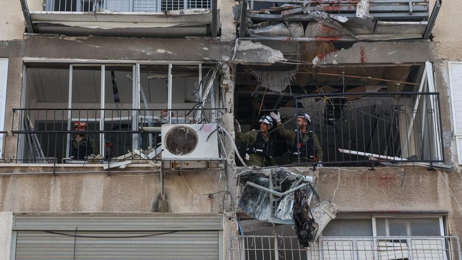 People gather near destroyed vehicles following an Iranian projectile strike, amid the U.S.-Israeli conflict with Iran, in central Israel, March 15, 2026. REUTERS/Tyrone Siu