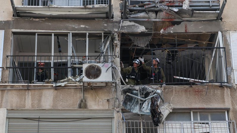 People gather near destroyed vehicles following an Iranian projectile strike, amid the U.S.-Israeli conflict with Iran, in central Israel, March 15, 2026. REUTERS/Tyrone Siu