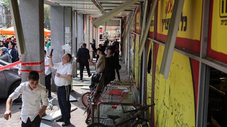 People gather near destroyed vehicles following an Iranian projectile strike, amid the U.S.-Israeli conflict with Iran, in central Israel, March 15, 2026. REUTERS/Tyrone Siu
