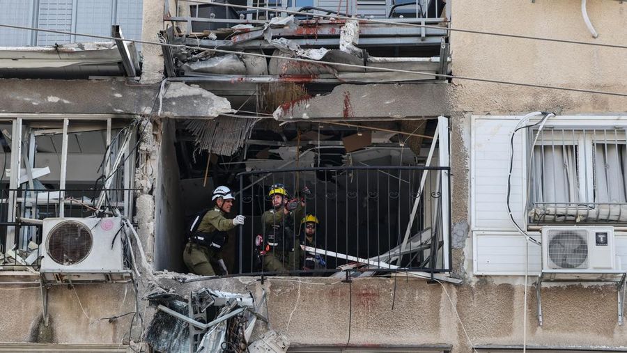People gather near destroyed vehicles following an Iranian projectile strike, amid the U.S.-Israeli conflict with Iran, in central Israel, March 15, 2026. REUTERS/Tyrone Siu