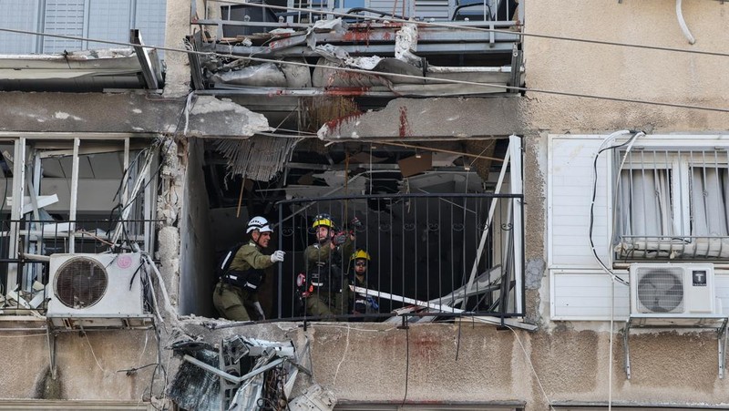 People gather near destroyed vehicles following an Iranian projectile strike, amid the U.S.-Israeli conflict with Iran, in central Israel, March 15, 2026. REUTERS/Tyrone Siu