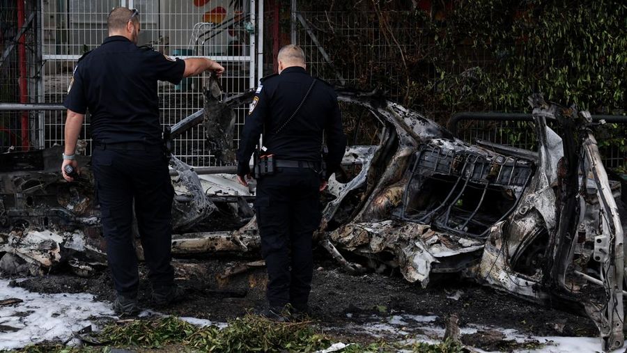 People gather near destroyed vehicles following an Iranian projectile strike, amid the U.S.-Israeli conflict with Iran, in central Israel, March 15, 2026. REUTERS/Tyrone Siu