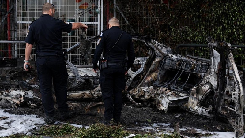 People gather near destroyed vehicles following an Iranian projectile strike, amid the U.S.-Israeli conflict with Iran, in central Israel, March 15, 2026. REUTERS/Tyrone Siu
