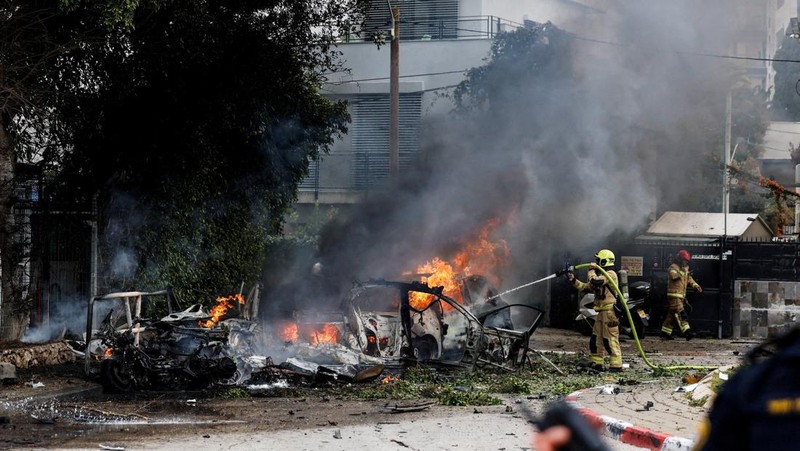 People gather near destroyed vehicles following an Iranian projectile strike, amid the U.S.-Israeli conflict with Iran, in central Israel, March 15, 2026. REUTERS/Tyrone Siu
