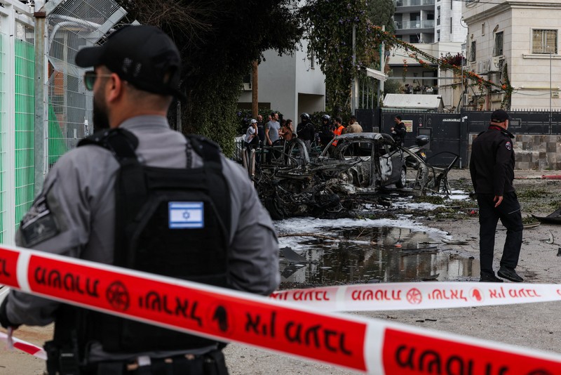 People gather near destroyed vehicles following an Iranian projectile strike, amid the U.S.-Israeli conflict with Iran, in central Israel, March 15, 2026. REUTERS/Tyrone Siu